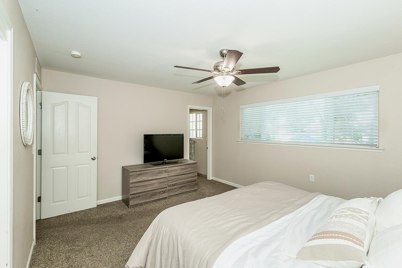 1563 South Klein Avenue Reedley, CA 93654 - Photo 33 of 81 a bedroom with a large bed a flat tv screen and a chandelier