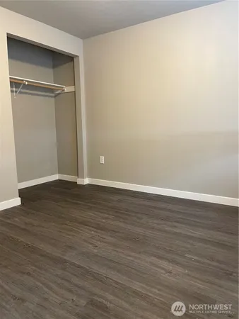 a view of an empty room with wooden floor & closet