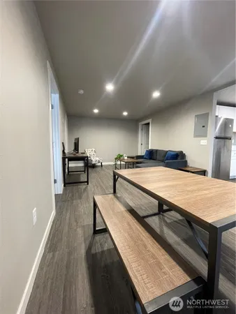 a living room with stainless steel appliances furniture a rug and a kitchen view
