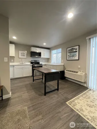 a living room with stainless steel appliances furniture a kitchen view and a refrigerator