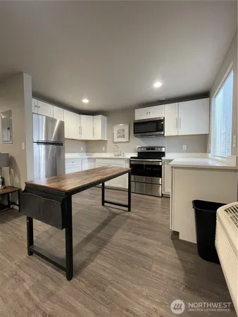a living room with stainless steel appliances furniture a fireplace and a view of kitchen
