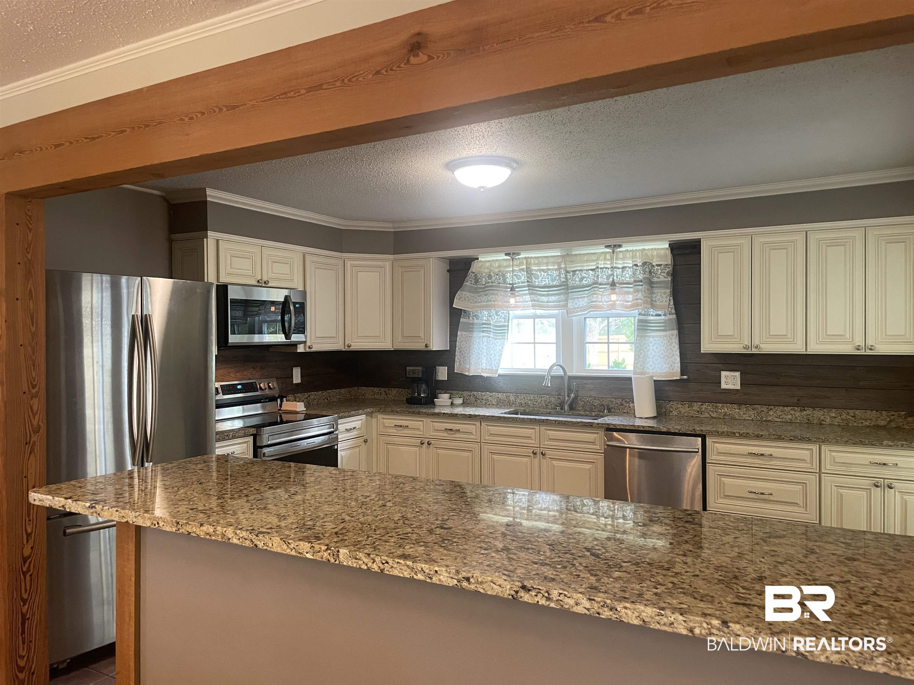 13850 Celeste Road Chunchula, AL 36521 - Photo 9 of 29 Kitchen featuring ornamental molding, a textured ceiling, stainless steel appliances, dark stone counters, and white cabinets