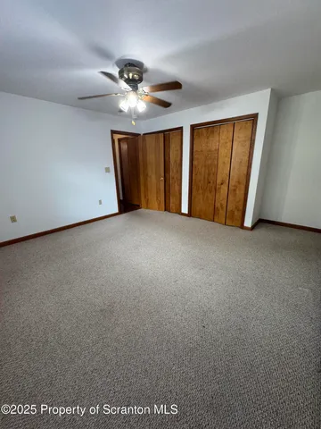 an empty room with windows and chandelier fan