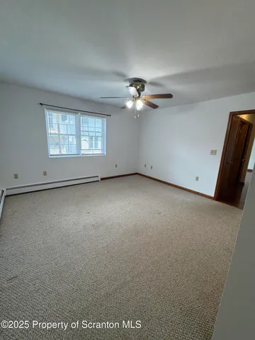 an empty room with windows and fan