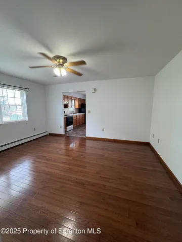 an empty room with wooden floor chandelier fan and windows
