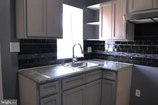 a kitchen with granite countertop a sink a stove and cabinets