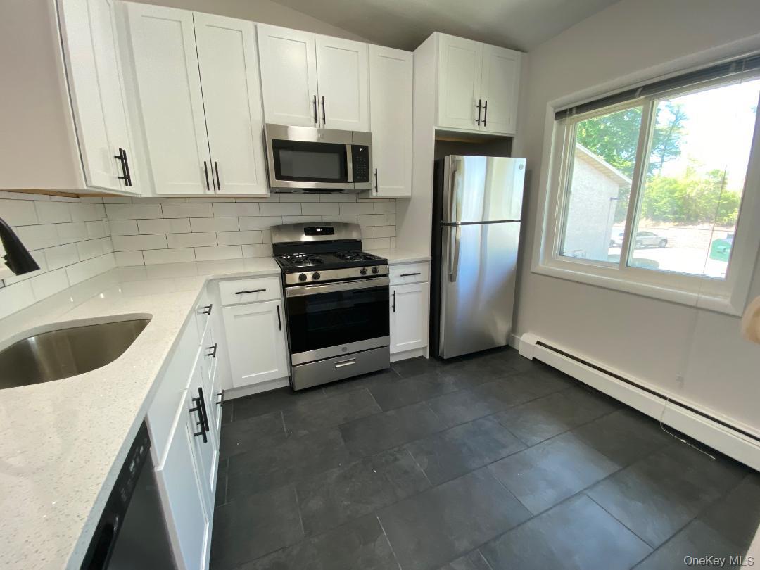 85 North Middletown Road, Unit E3 Nanuet, NY 10954 - Photo 3 of 20 Beautifully just renovated eat in kitchen featuring lots white shaker cabinetry with dark hardware, quartz counters, stainless steel appliances, subway tile backsplash, and pretty tile floor.