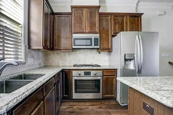 a kitchen with granite countertop a stove top oven and refrigerator