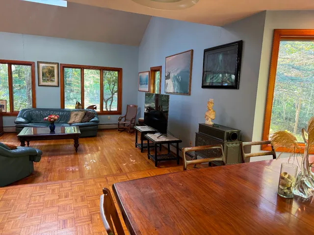 a living room with furniture a rug wooden floor and a large window