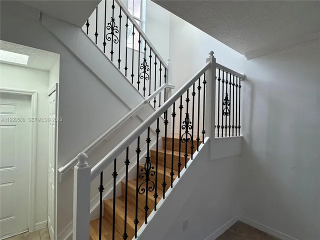 a view of staircase with wooden floor and white walls