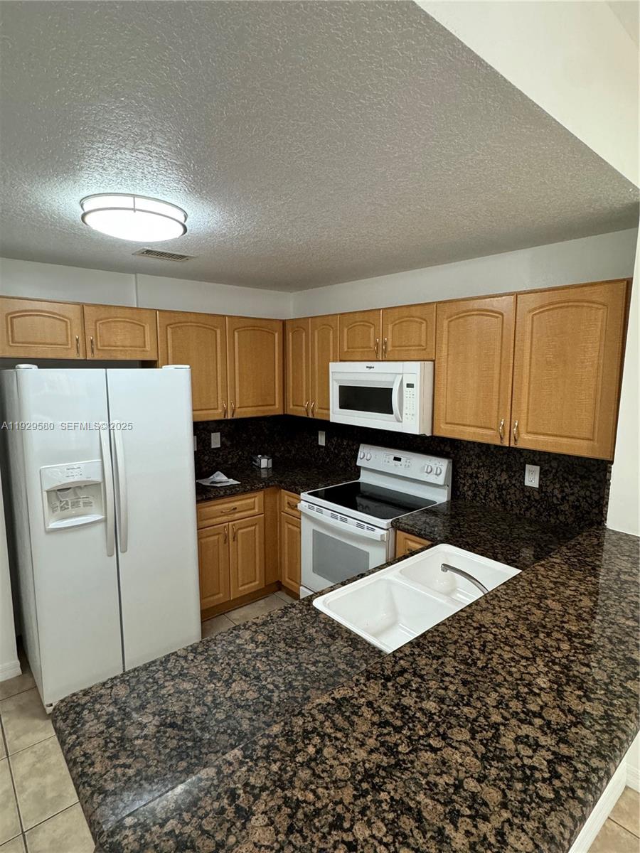 8507 Northwest 140th Terrace, Unit 801 Miami Lakes, FL 33016 - Photo 34 of 42 a kitchen with stainless steel appliances kitchen island granite countertop a refrigerator and a stove top oven