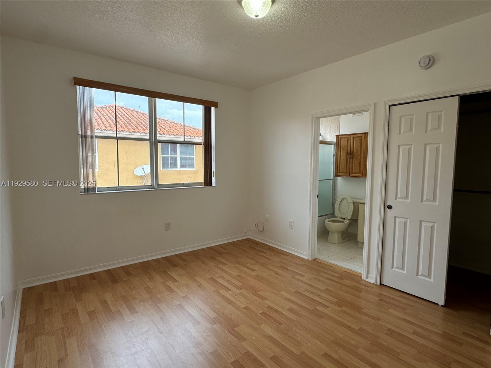 8507 Northwest 140th Terrace, Unit 801 Miami Lakes, FL 33016 - Photo 37 of 42 an empty room with wooden floor and a window