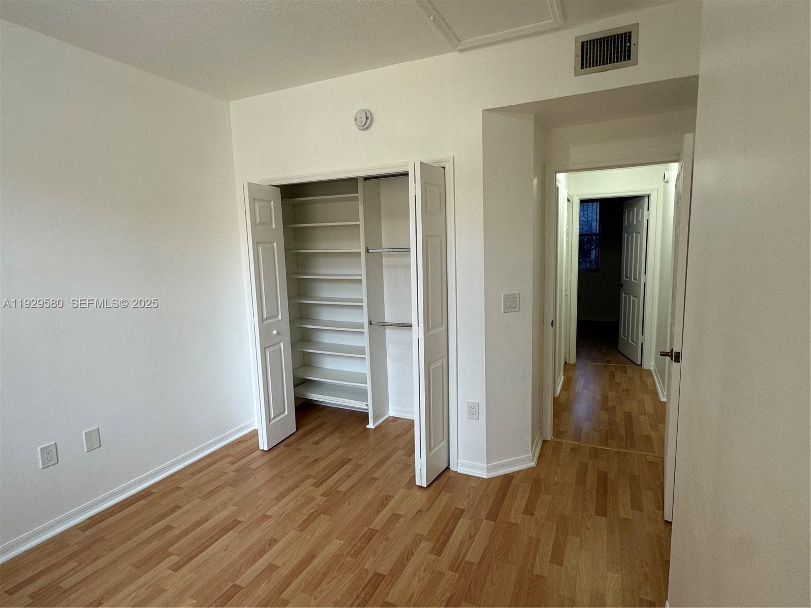 8507 Northwest 140th Terrace, Unit 801 Miami Lakes, FL 33016 - Photo 40 of 42 an empty room with wooden floor and closet