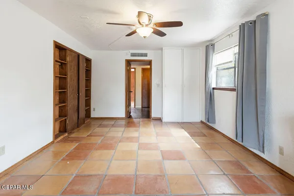 a view of an empty room with window and chandelier fan