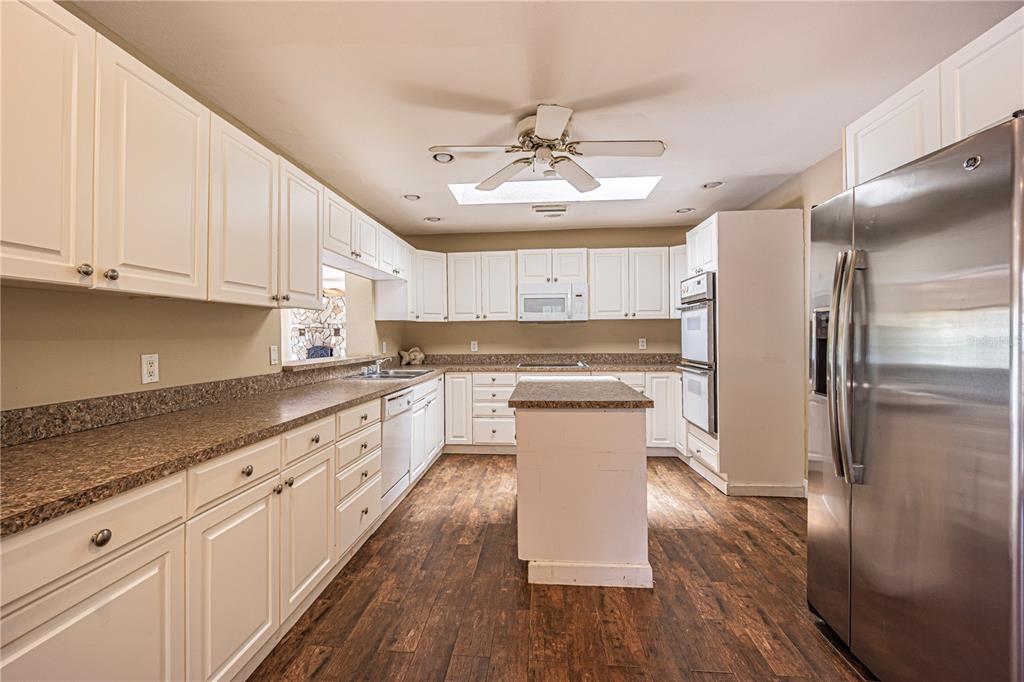 18129 Crawley Road Odessa, FL 33556 - Photo 13 of 38 a kitchen with stainless steel appliances granite countertop a refrigerator a sink dishwasher a stove and white countertops with wooden floor