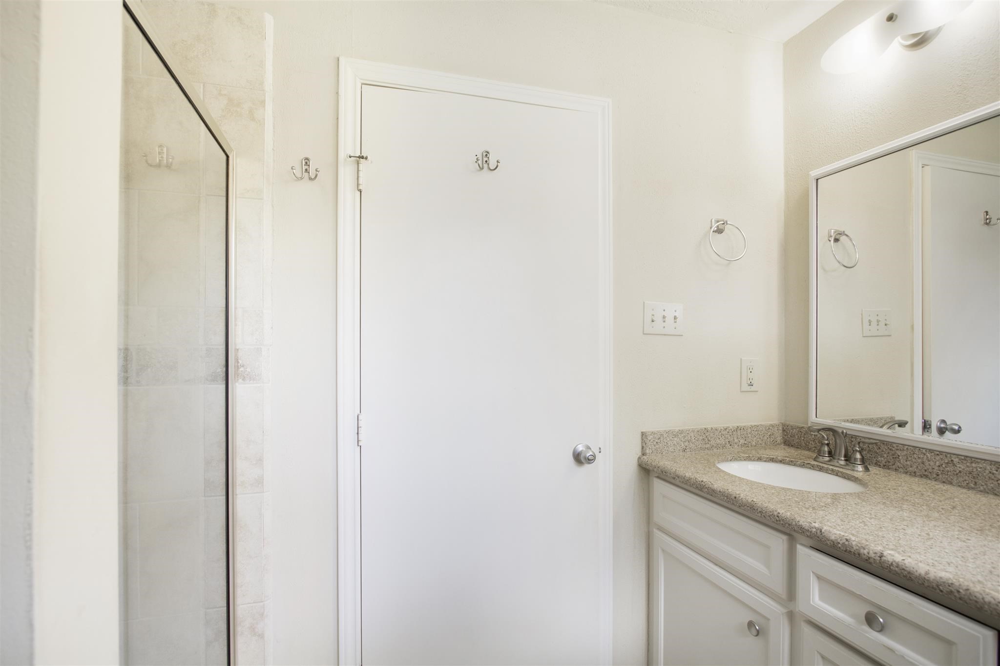 6019 Spellman Road Houston, TX 77096 - Photo 15 of 19 a bathroom with a granite countertop sink a mirror and a shower