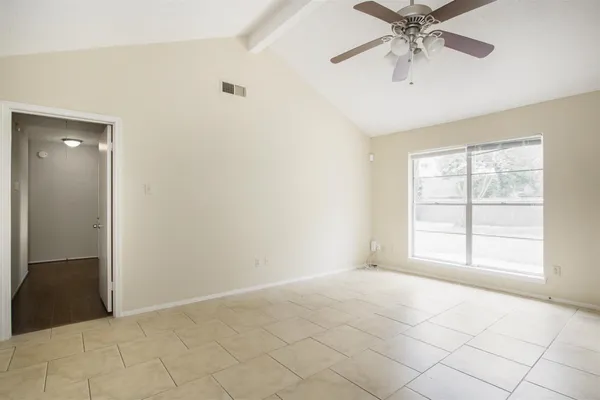 an empty room with chandelier fan and windows