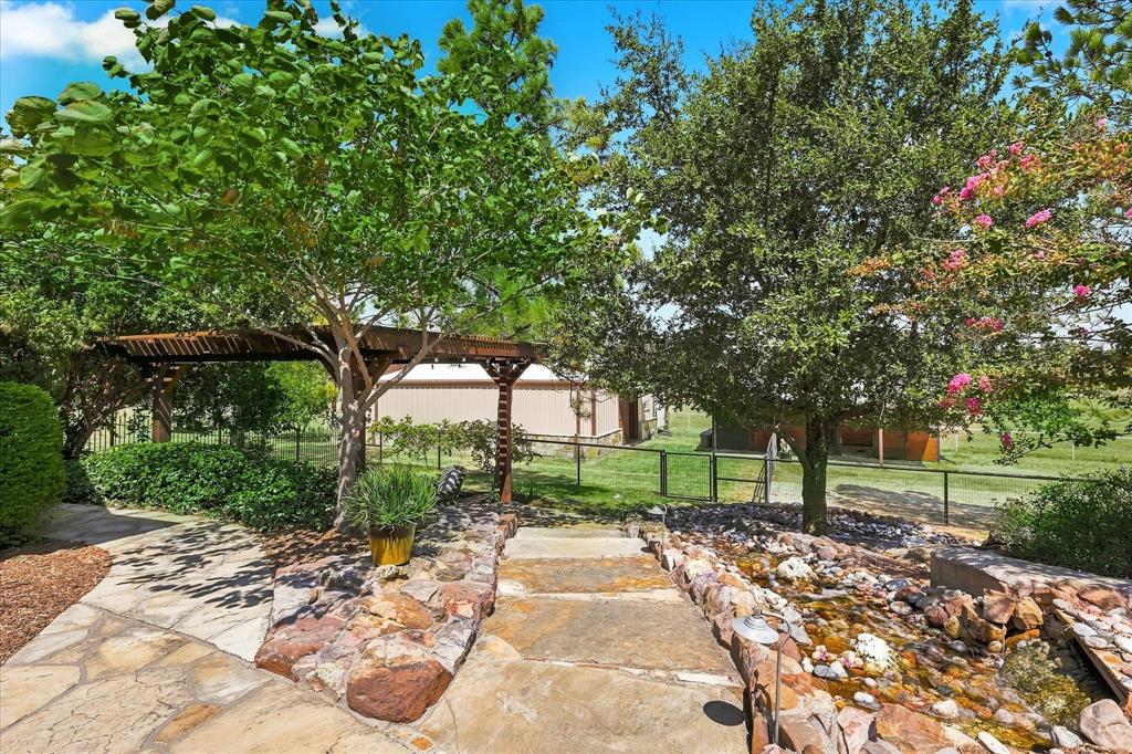 9229 Hub Clark Road Pilot Point, TX 76258 - Photo 27 of 35 Stairs to barn with waterfall feature and a Grotto sitting area with pergola cover.