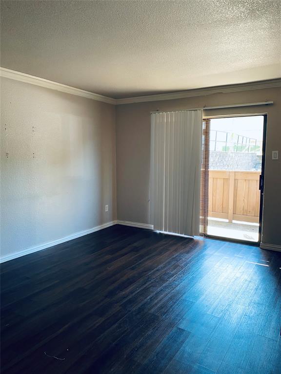 Unfurnished room with wood finished floors, a textured ceiling, and ornamental molding