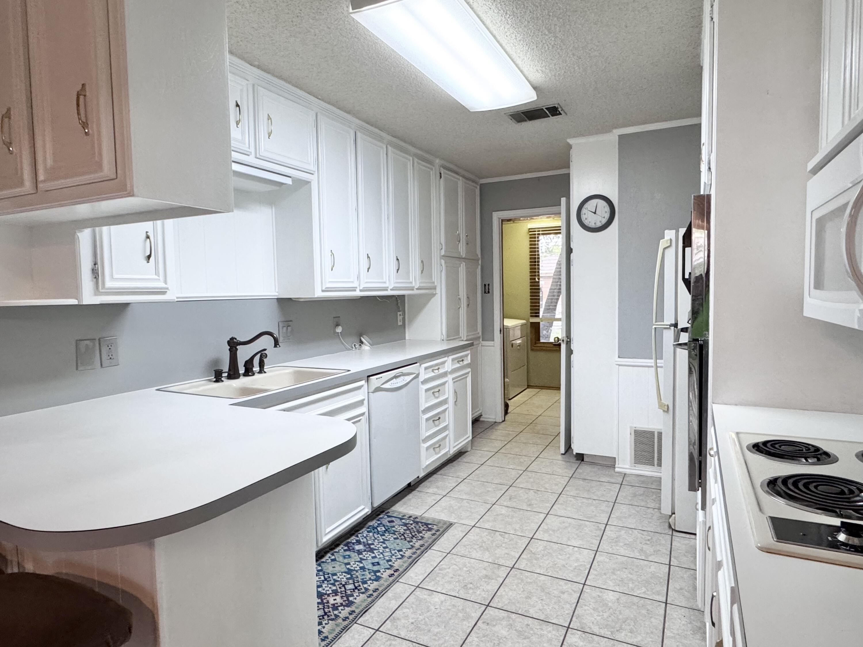 5617 87th Street Lubbock, TX 79424 - Photo 13 of 22 a kitchen with granite countertop a sink a stove a refrigerator and cabinets