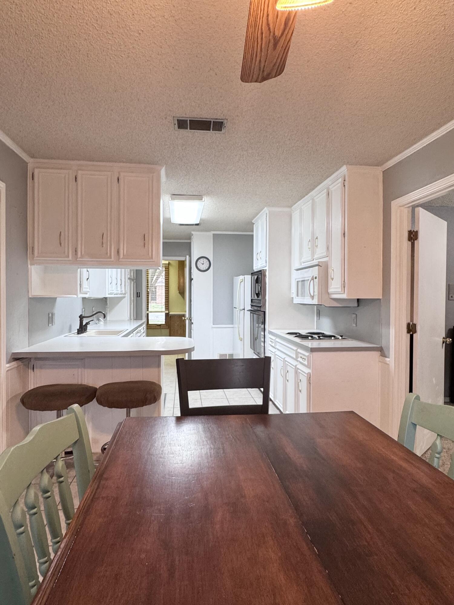 5617 87th Street Lubbock, TX 79424 - Photo 4 of 22 a kitchen with granite countertop a refrigerator and white cabinets