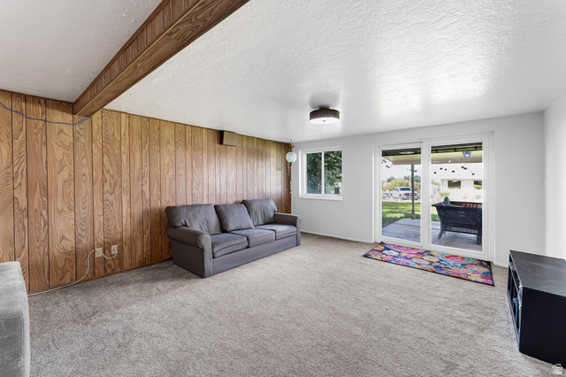 88 West 700 South Payson, UT 84651 - Photo 12 of 27 Carpeted living room featuring a textured ceiling, beam ceiling, and wooden walls