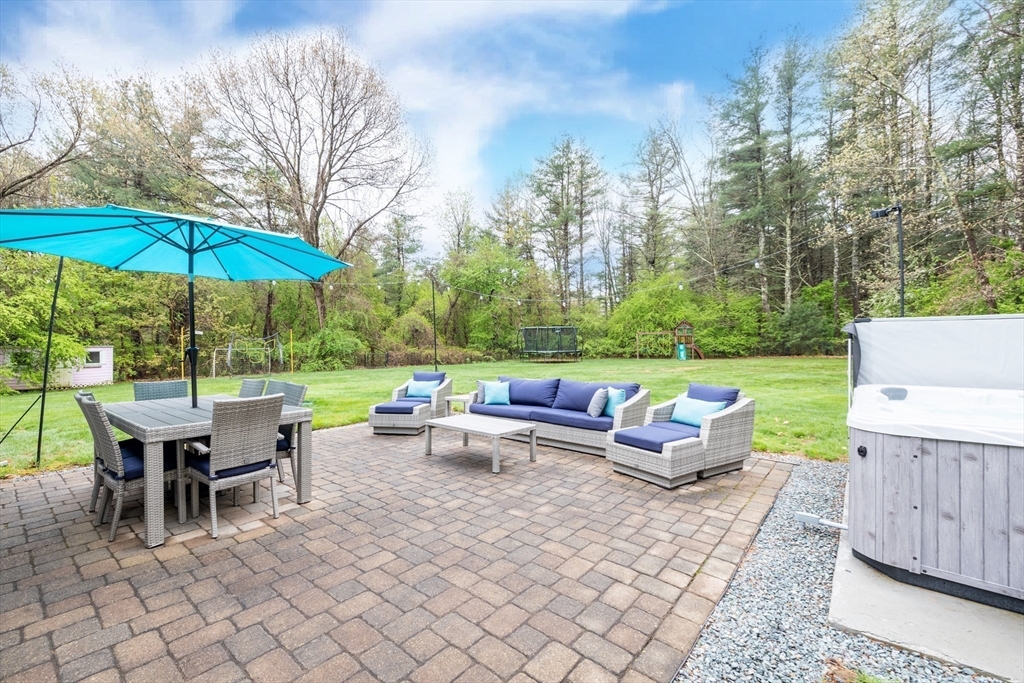26 Roundtop Road Boxford, MA 01921 - Photo 6 of 42 a view of a patio with a dining table and chairs under an umbrella