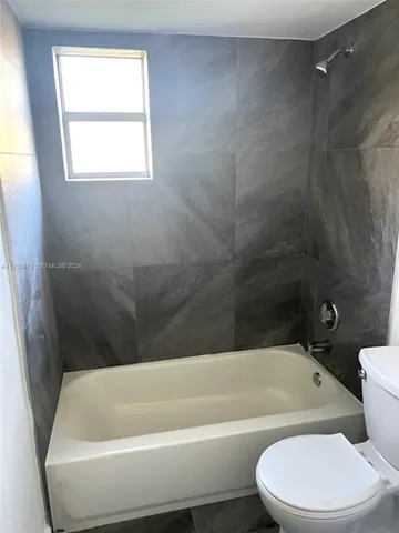 a bathroom with a toilet bathtub window and shower