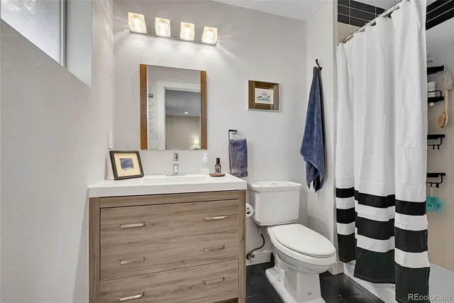 a bathroom with a sink a toilet a mirror and shower curtain