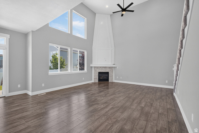36 West Syracuse Road Vineyard, UT 84059 - Photo 11 of 56 Spacious living area featuring high vaulted ceilings, expansive windows, wood-finish flooring, a contemporary ceiling fan, and a built-in fireplace with a tiled surround