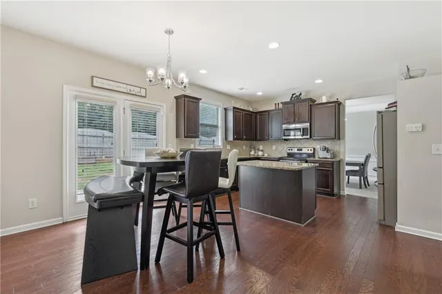 a kitchen with stainless steel appliances a dining table chairs stove refrigerator and cabinets