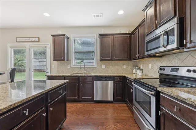 a kitchen with stainless steel appliances granite countertop a sink stove and microwave