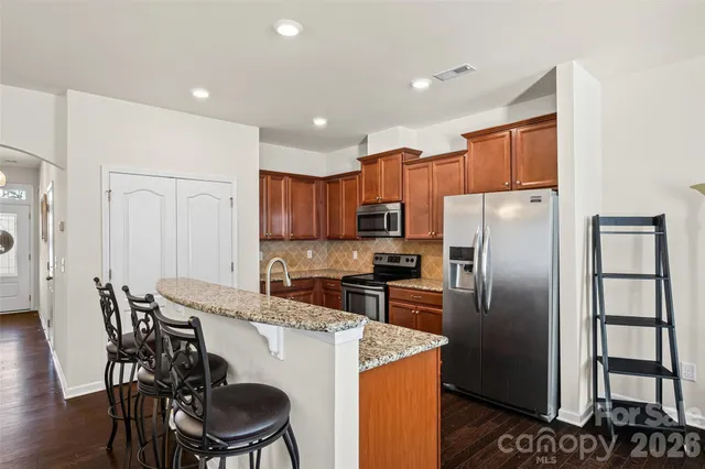 a kitchen with stainless steel appliances a refrigerator a stove a sink a dining table and chairs