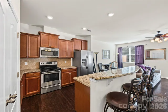 a kitchen with stainless steel appliances a dining table chairs microwave and stove
