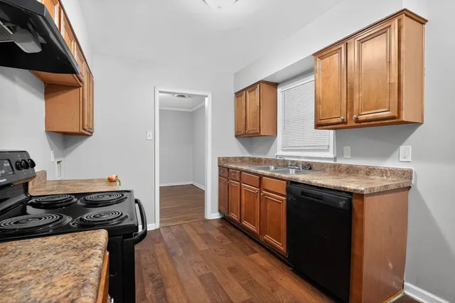 a kitchen with granite countertop a sink a stove and wooden cabinets