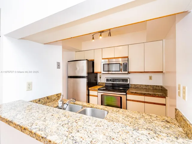 a kitchen with stainless steel appliances granite countertop a refrigerator a stove and a sink with granite countertops