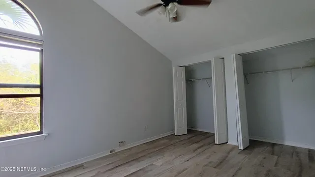 an empty room with wooden floor closet and windows