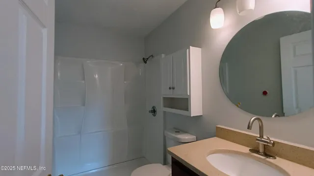 a bathroom with a granite countertop sink toilet a mirror and shower