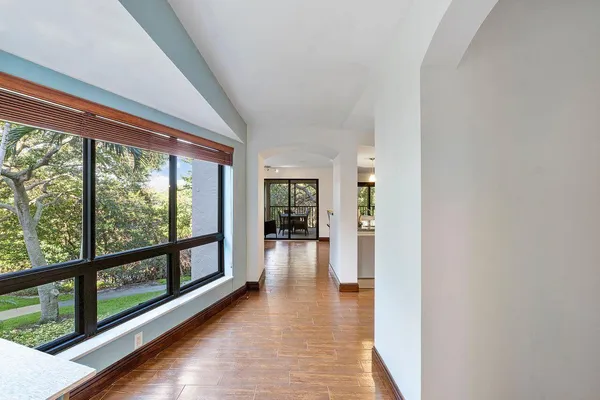 a view of a hallway with wooden floor and a kitchen