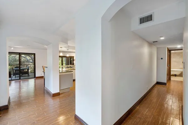 a view of a living room kitchen with stainless steel appliances wooden floor and a large window