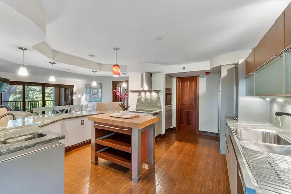 a kitchen with stainless steel appliances granite countertop a sink a stove and a wooden floors