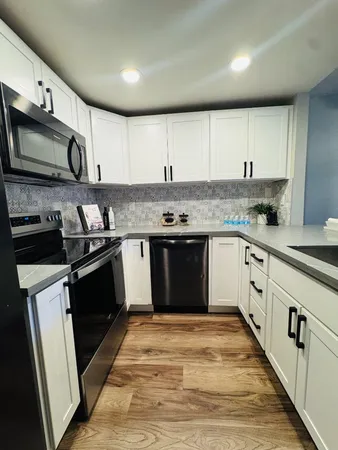 a kitchen with stainless steel appliances granite countertop a stove top oven a sink dishwasher a refrigerator and a microwave