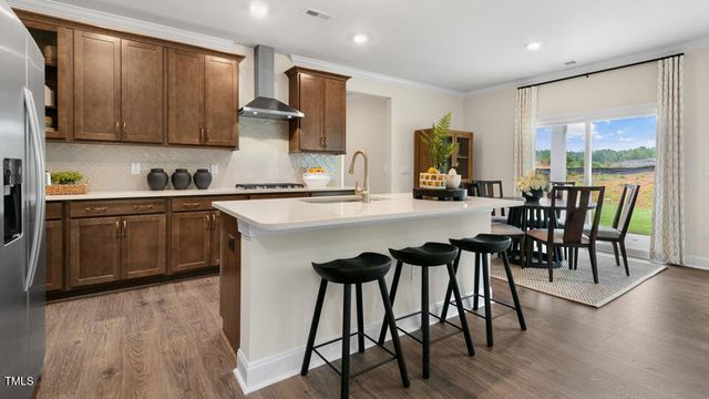 a kitchen with stainless steel appliances granite countertop a stove top oven a sink a dining table and chairs with wooden floor