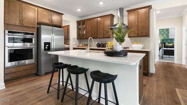 a kitchen with stainless steel appliances a dining table chairs refrigerator and microwave