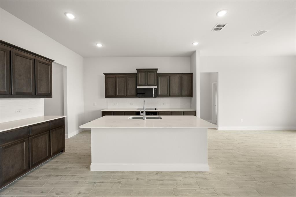 228 Shepards Street Godley, TX 76044 - Photo 3 of 27 a large kitchen with stainless steel appliances a sink a stove a microwave a counter top and cabinets