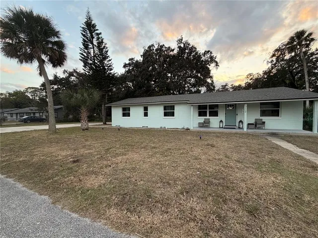 a front view of house with yard and trees in the background