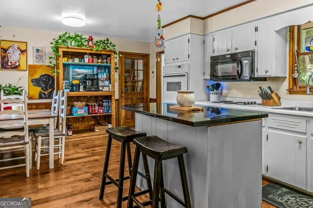 a kitchen with stainless steel appliances granite countertop a refrigerator a stove a sink dishwasher and white cabinets with wooden floor