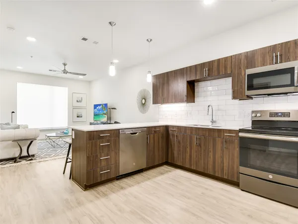 a kitchen with stainless steel appliances granite countertop a refrigerator a stove a sink a dining table and chairs with wooden floor