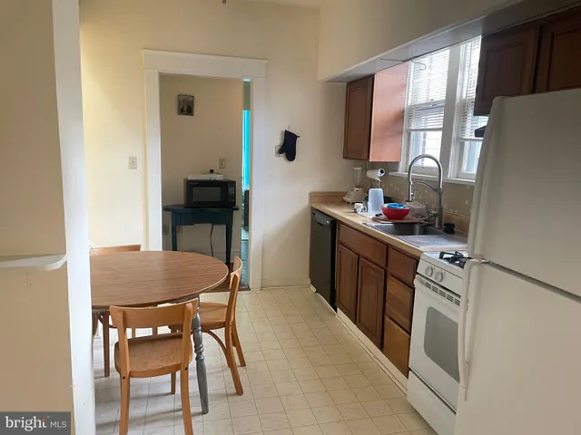 a kitchen with stainless steel appliances granite countertop a stove a sink dishwasher a refrigerator a dining table and chairs with wooden floor