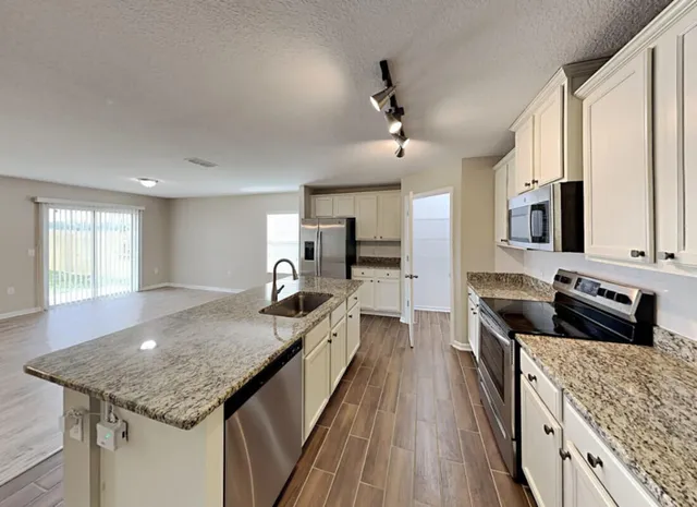 a kitchen with stainless steel appliances granite countertop a sink dishwasher stove and oven with wooden floor